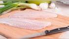 Filete de pescado descongelado sobre tabla de picar con cuchillo