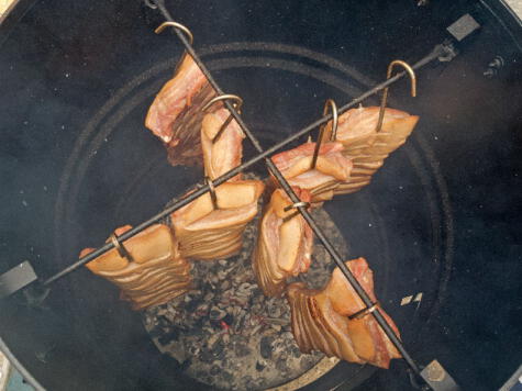 Las carnes van colgadas de ganchos, con el carbón en la base, generando el efecto de un horno ahumador.   