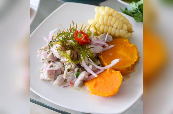 Ceviche peruano tradicional: pescado fresco marinado en jugo de limón, acompañado de camote, maíz y ají limo.   