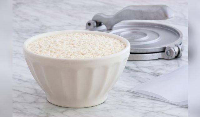 Maíz nixtamalizado o nixtamal y la prensa para hacer tortillas.   