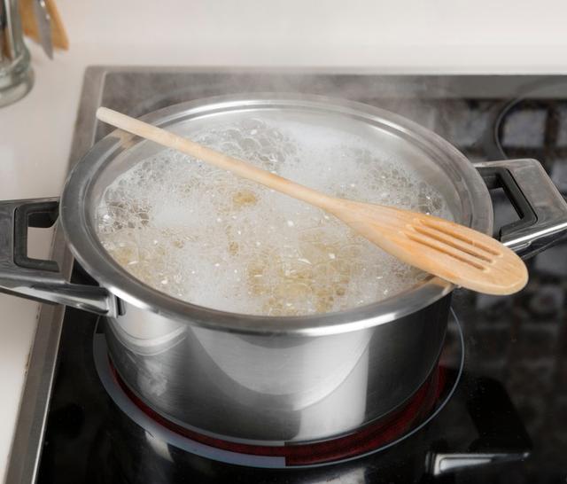 Coloca una cuchara de madera sobre la olla hirviendo.   